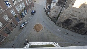 Una calle adoquinada con edificios históricos, una fuente y una plaza circular.