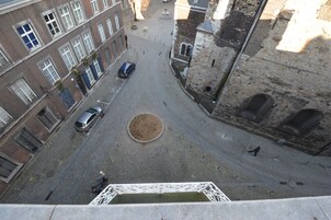 A cobblestone street with historic buildings, a fountain, and a circular plaza.