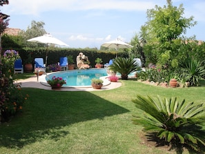 A backyard with a swimming pool, surrounded by potted plants and outdoor furniture. - SVS - Isuledda Villas (San Teodoro)