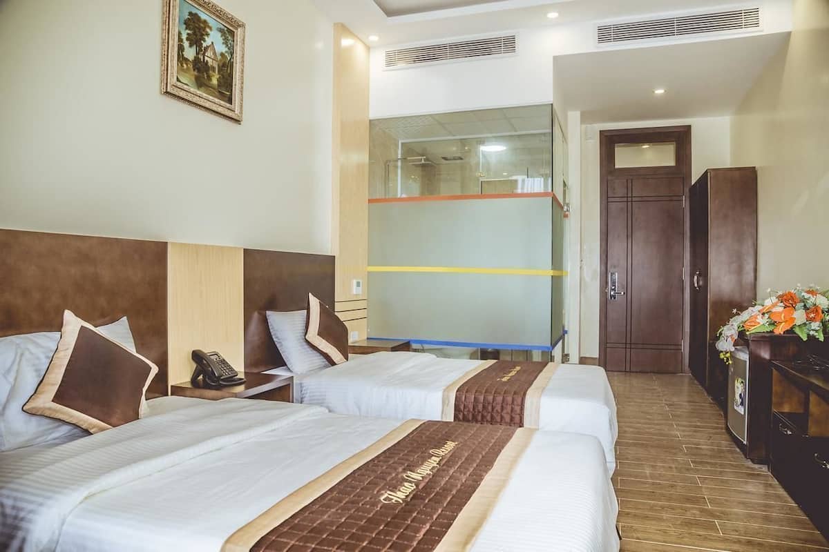 A hotel room with two beds, a telephone, a mirror, a wardrobe, and a picture on the wall.
