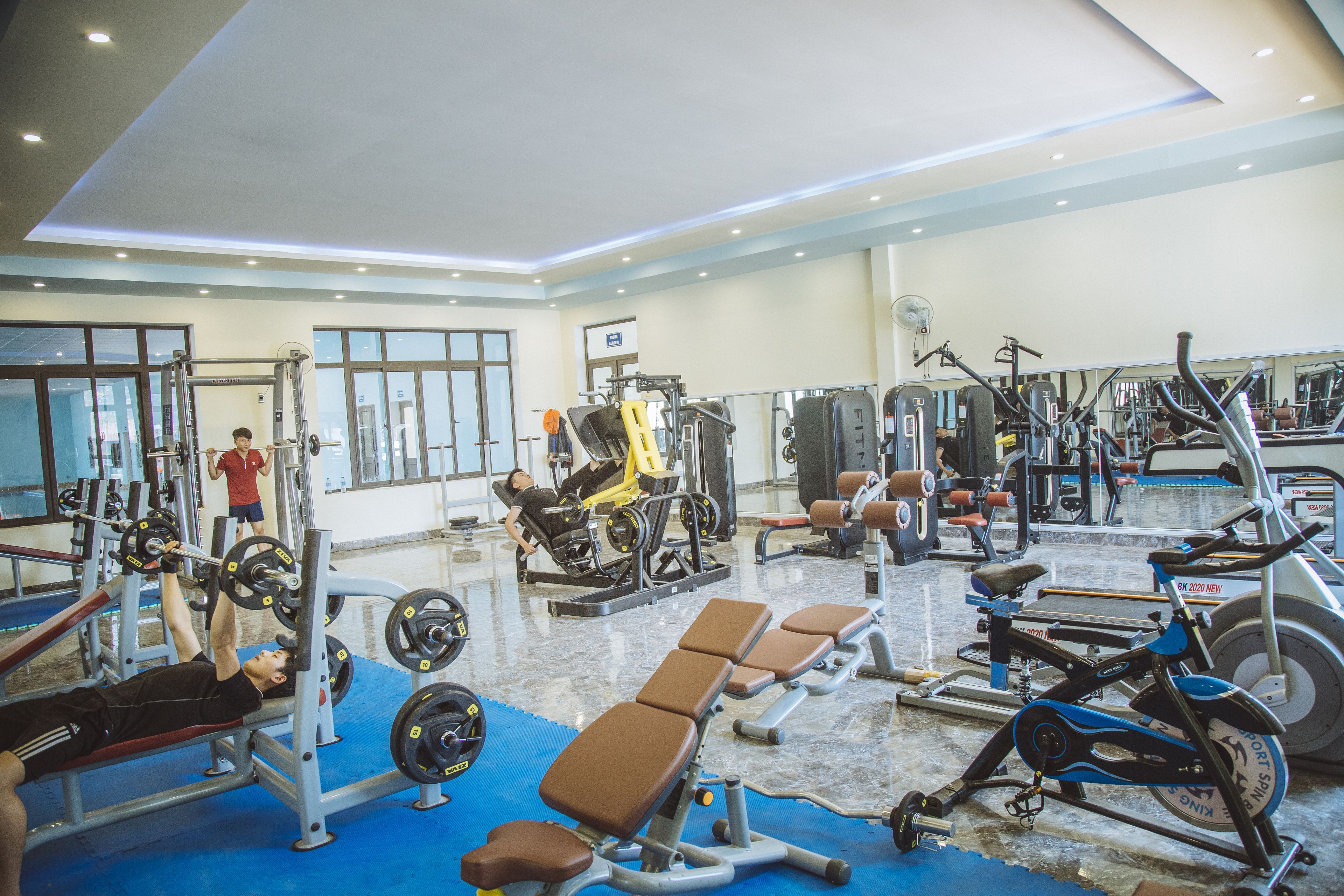 A gym with various exercise equipment, including weight machines, benches, and cardio machines.