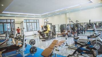 A gym with various exercise equipment, including weight machines, benches, and cardio machines.