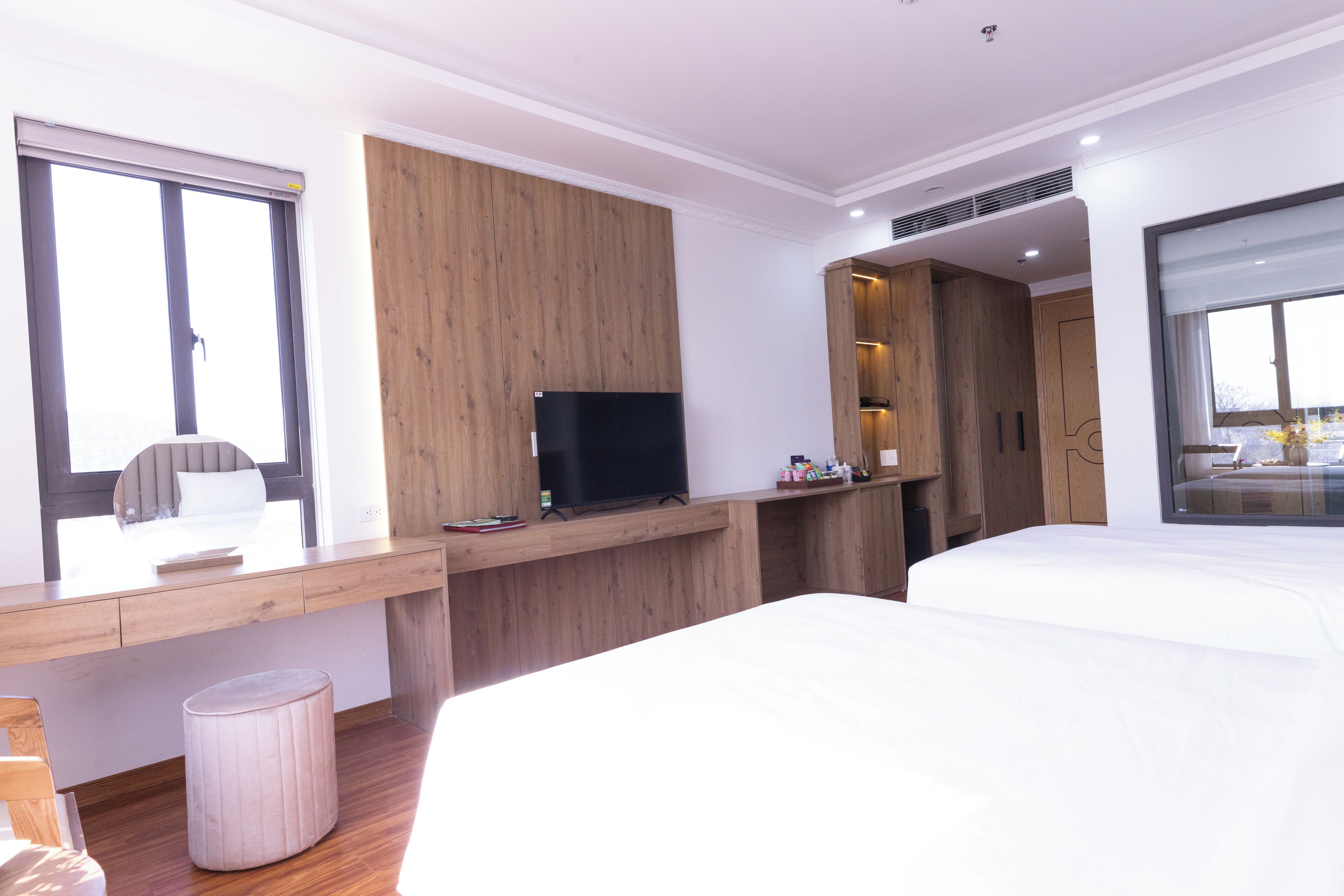 Una camera d'albergo moderna con una scrivania in legno, una TV a schermo piatto, un letto e una grande finestra.