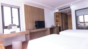 Una camera d'albergo moderna con una scrivania in legno, una TV a schermo piatto, un letto e una grande finestra.