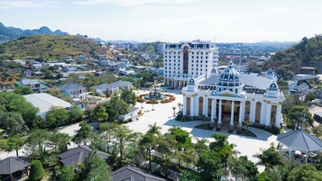 Un gran hotel con una fuente central, rodeado de exuberante vegetación y edificios residenciales.