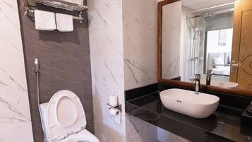 A modern bathroom with a toilet, a sink, and a large mirror.