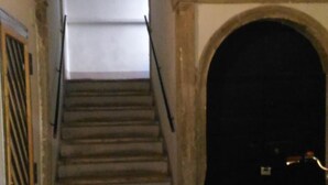 Una escalera con suelo de baldosas que conduce a una puerta oscura, enmarcada por un arco.