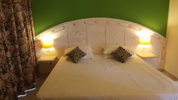 Un lit avec deux oreillers, deux lampes de chevet et un rideau à motifs floraux.
