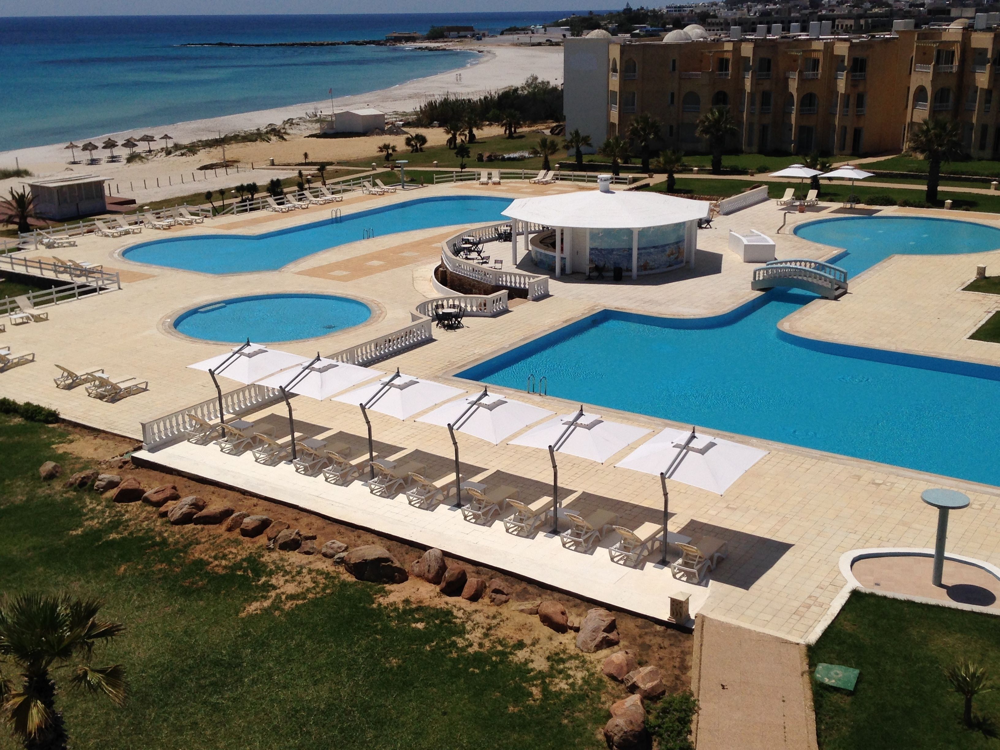 Un complexe hôtelier doté de plusieurs piscines, de chaises longues et offrant une vue sur la plage.