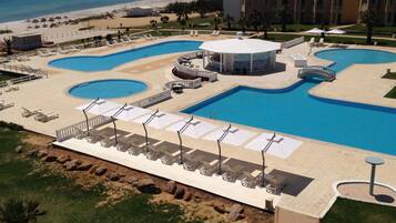 Un complexe hôtelier doté de plusieurs piscines, de chaises longues et offrant une vue sur la plage.