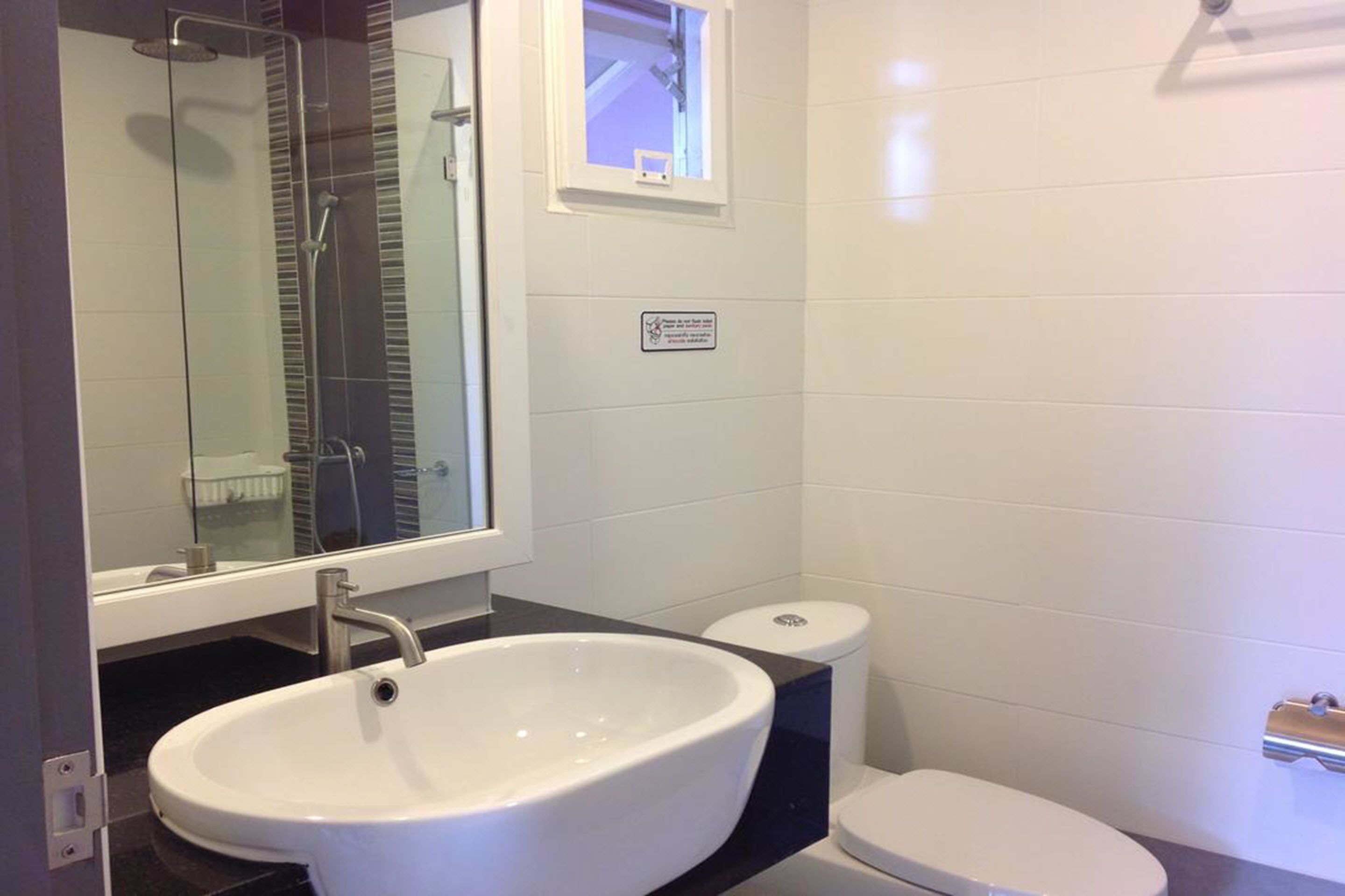 A bathroom with a white sink, a toilet, and a shower.