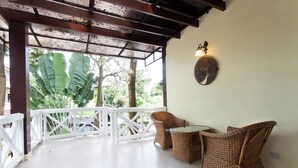 A covered patio area with wicker furniture and a wall-mounted clock. - Sandy House Rawai (Rawai)