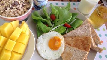 Un plato de desayuno con tostadas, un huevo frito, mango, ensalada y yogur.