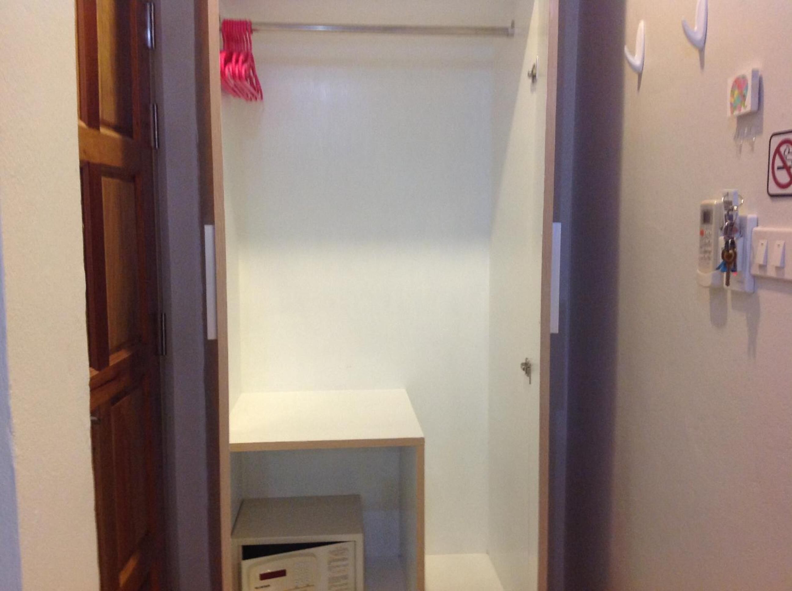 Un pasillo estrecho que conduce a un baño con ducha, un perchero y un estante con una caja.