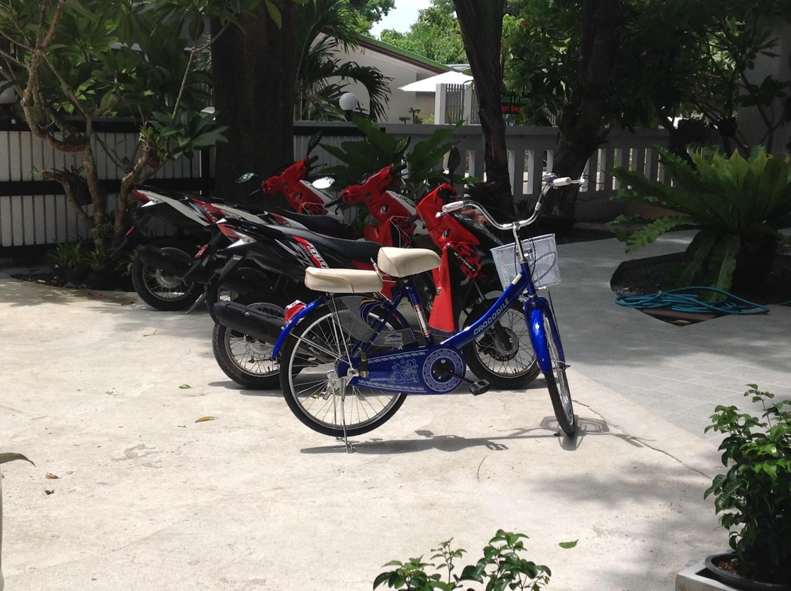 Una bicicleta azul con cesta y asiento blanco estacionada sobre una superficie de concreto.