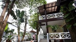 A courtyard with a two-story building, a white fence, and various potted plants. - Sandy House Rawai (Rawai)