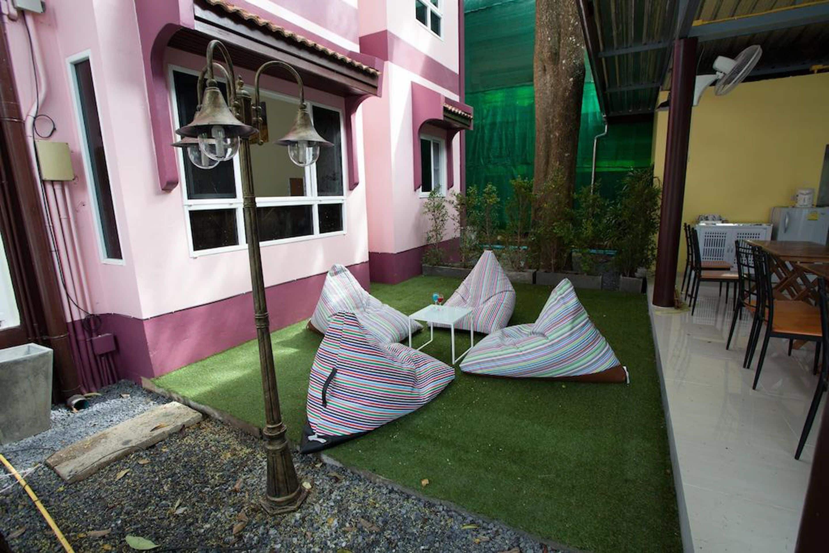 A pink building with a small patio area featuring striped bean bag chairs and a table.