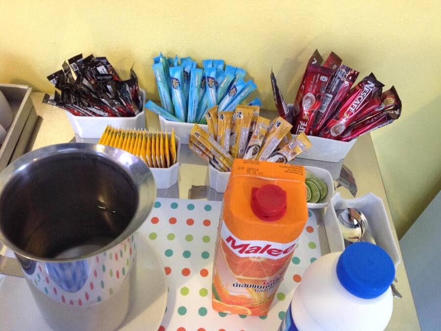 Una mesa con diversos alimentos y recipientes, incluyendo un mantel con lunares, un tazón de metal y una botella de jugo de naranja.