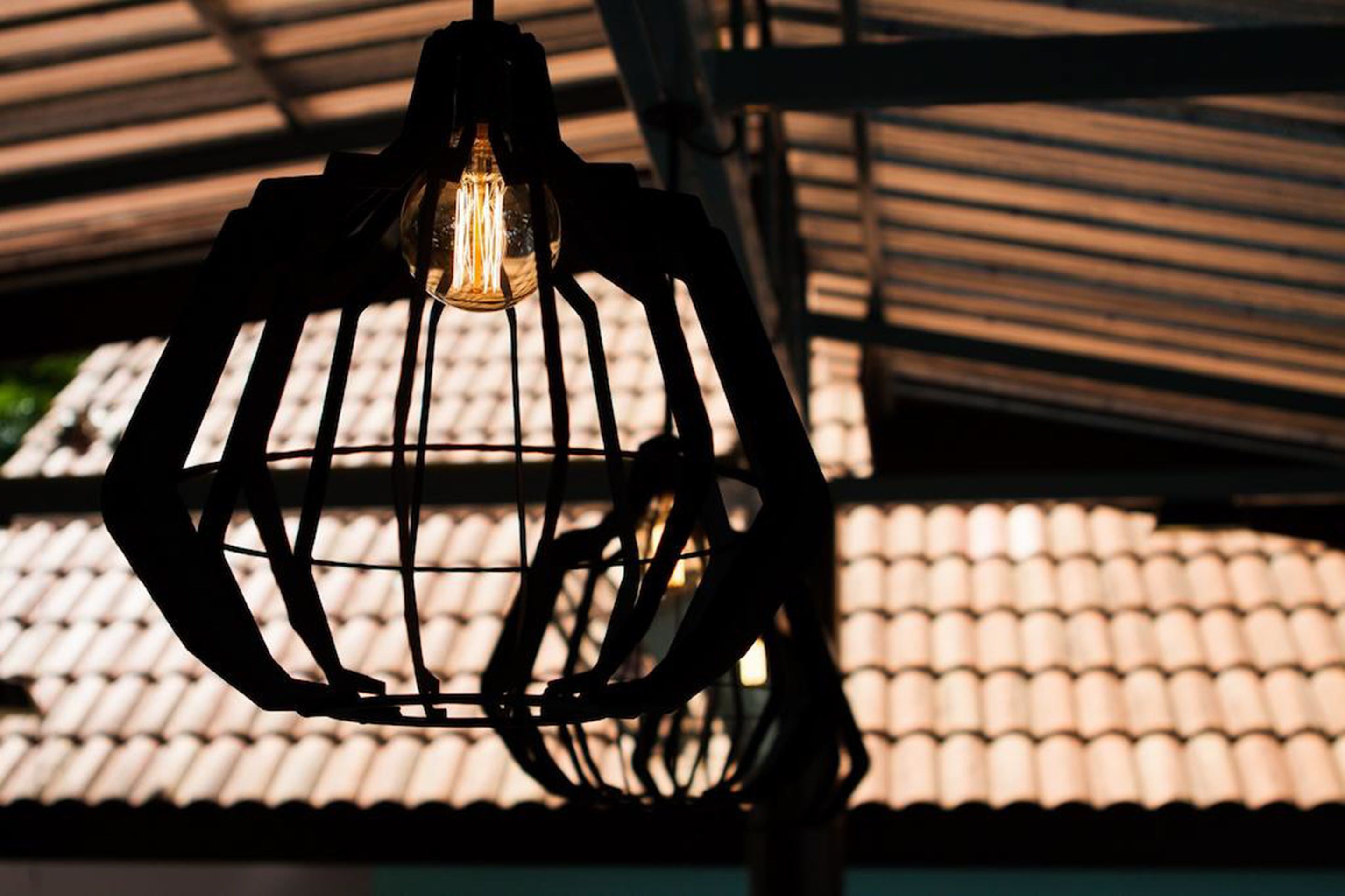 Un luminaire suspendu dont l’ampoule est visible.