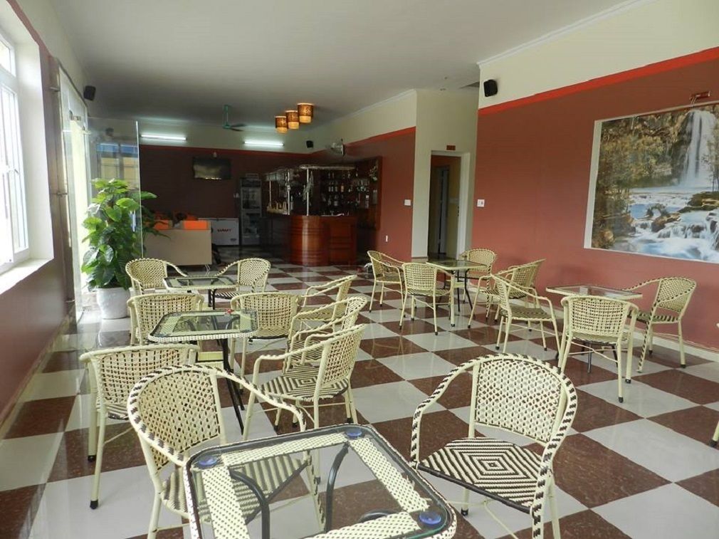 Un vestíbul amb sòl a escacs, mobles de vímet, una zona de bar i un quadre a la paret.