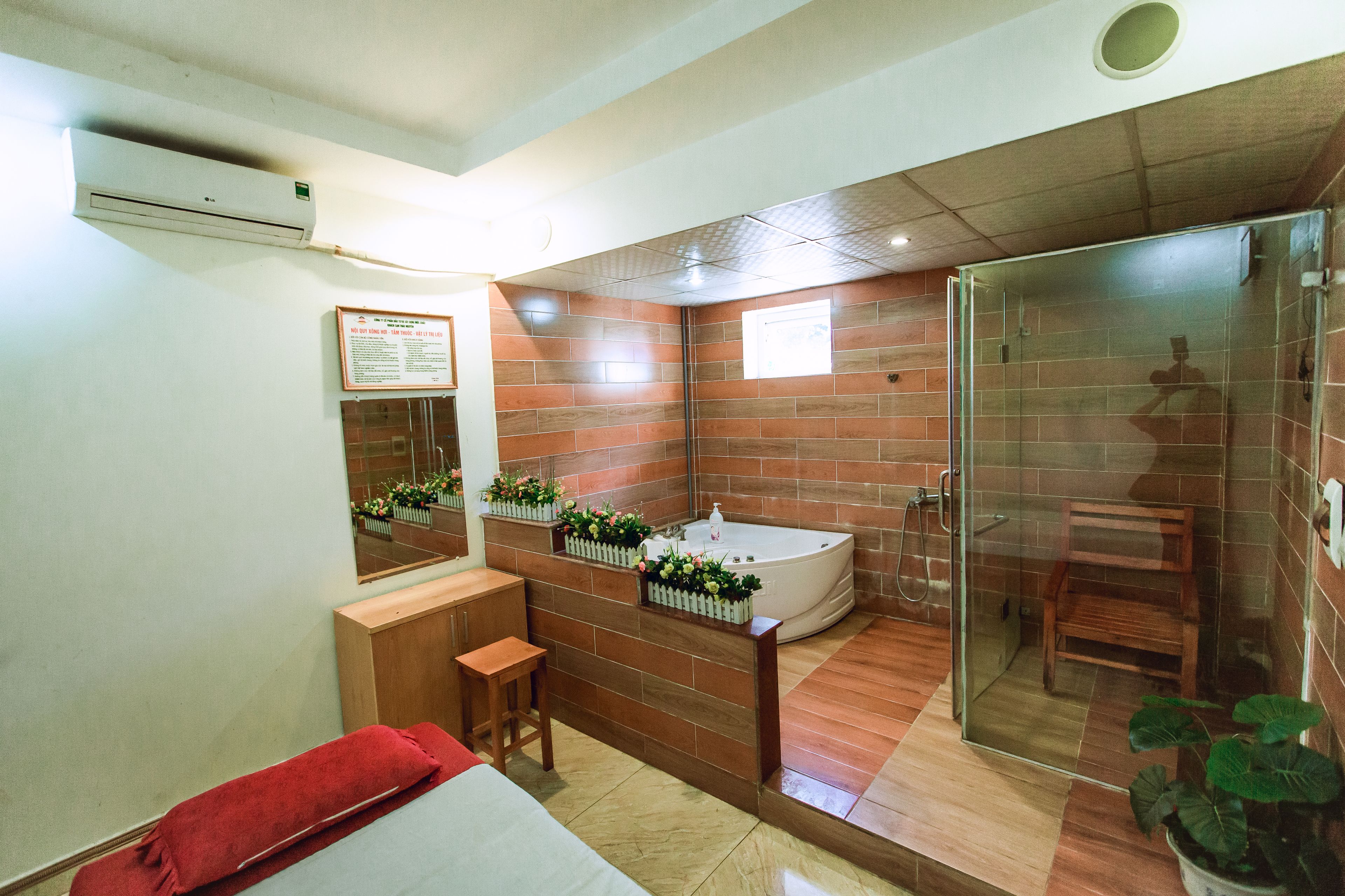 A modern bathroom with a large bathtub, a glass shower enclosure, and a wooden bench.