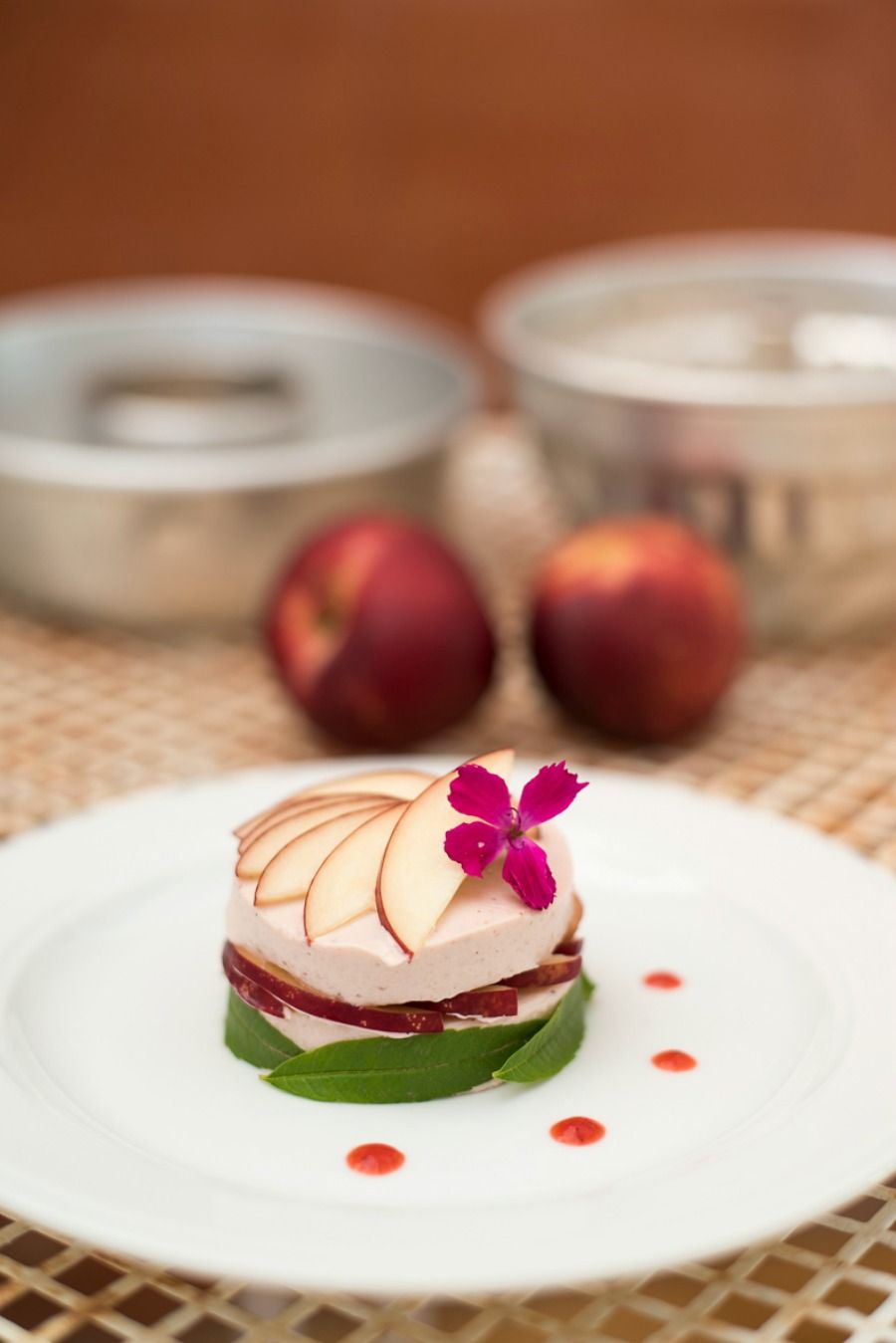 Un postre sobre un plato blanco con una flor decorativa, rodeado por un mantel tejido.
