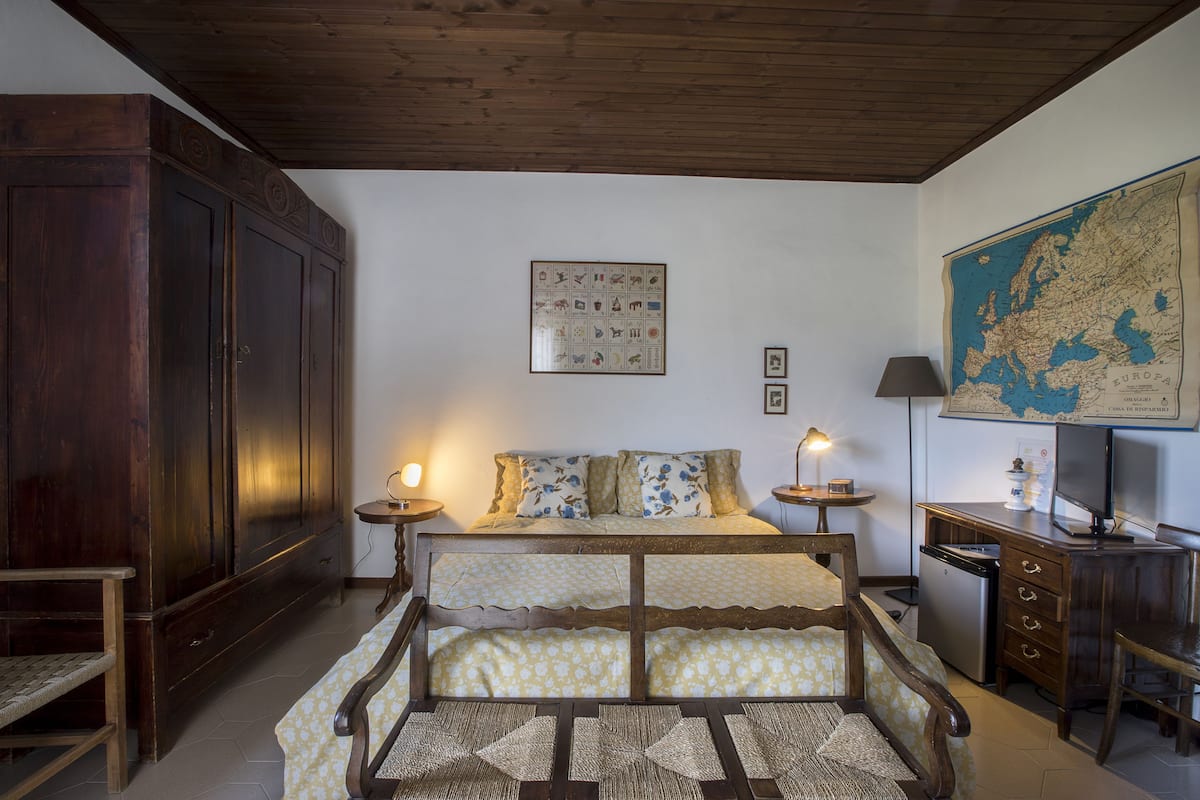 A room with a bed, a map on the wall, a desk, and a wardrobe.