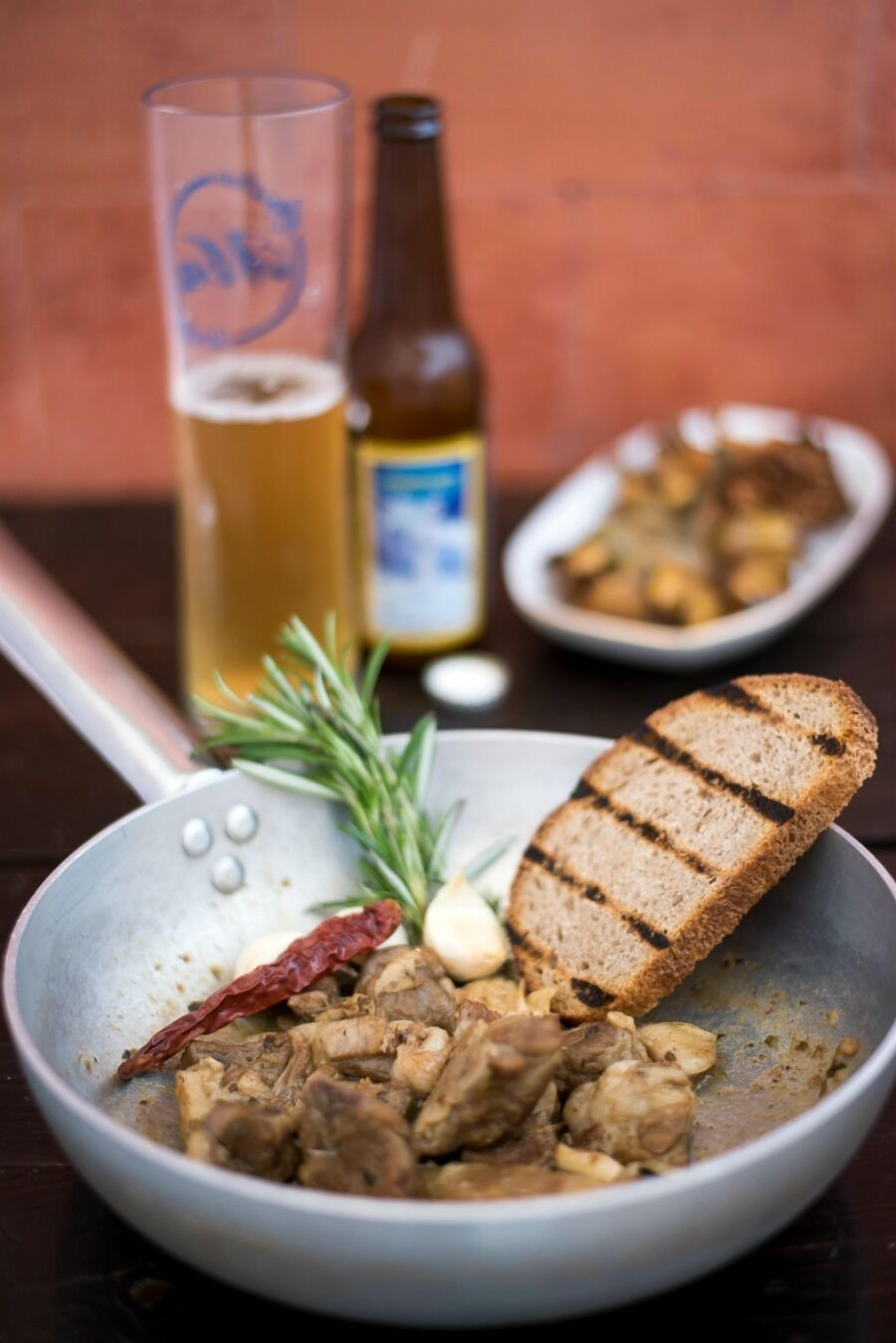 Un repas composé de viande grillée, de pain et d’un verre de bière, le tout servi sur une table.