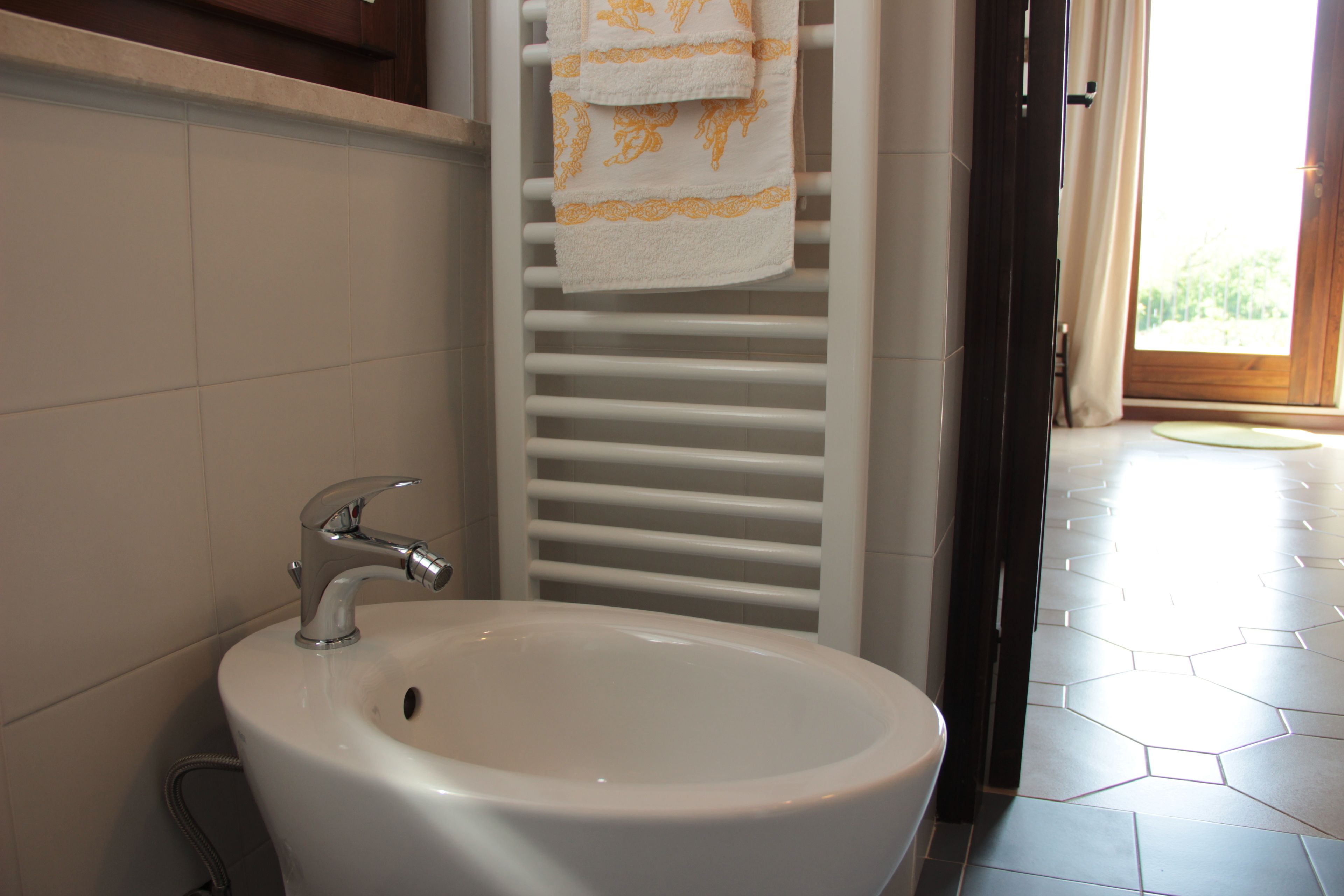 A bathroom with a white sink, a towel rack with a towel, and a shower area.