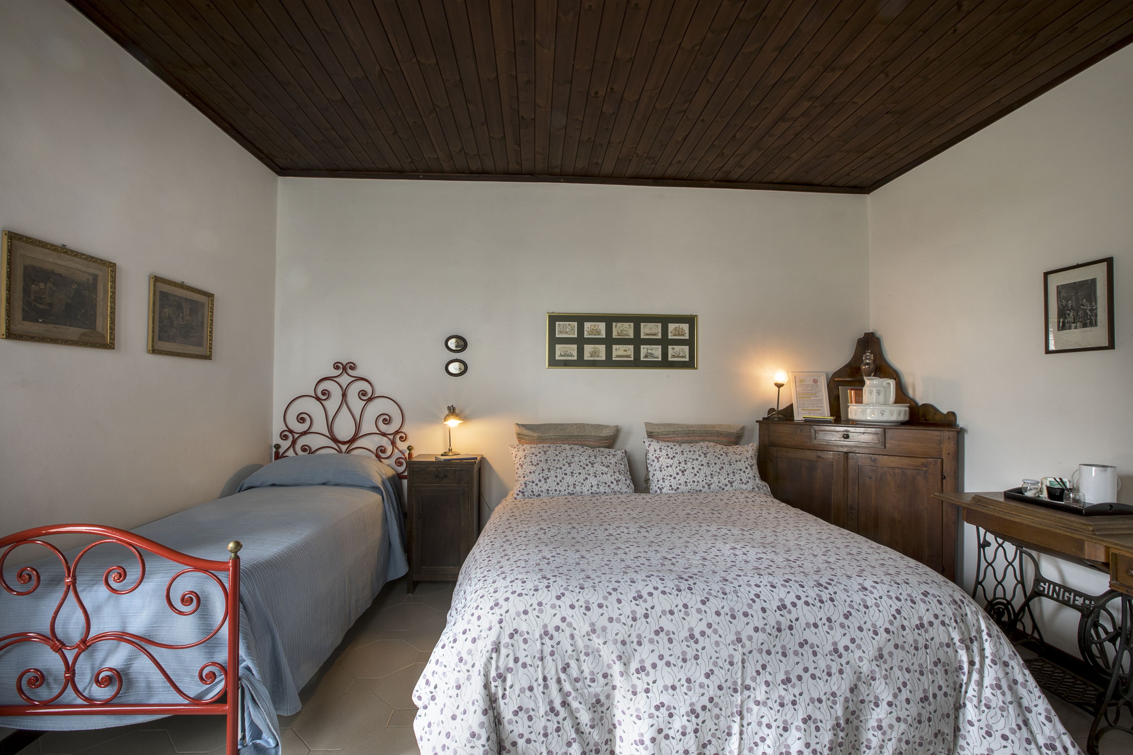 Une chambre avec deux lits, un plafond en bois, une commode et un bureau avec une chaise.