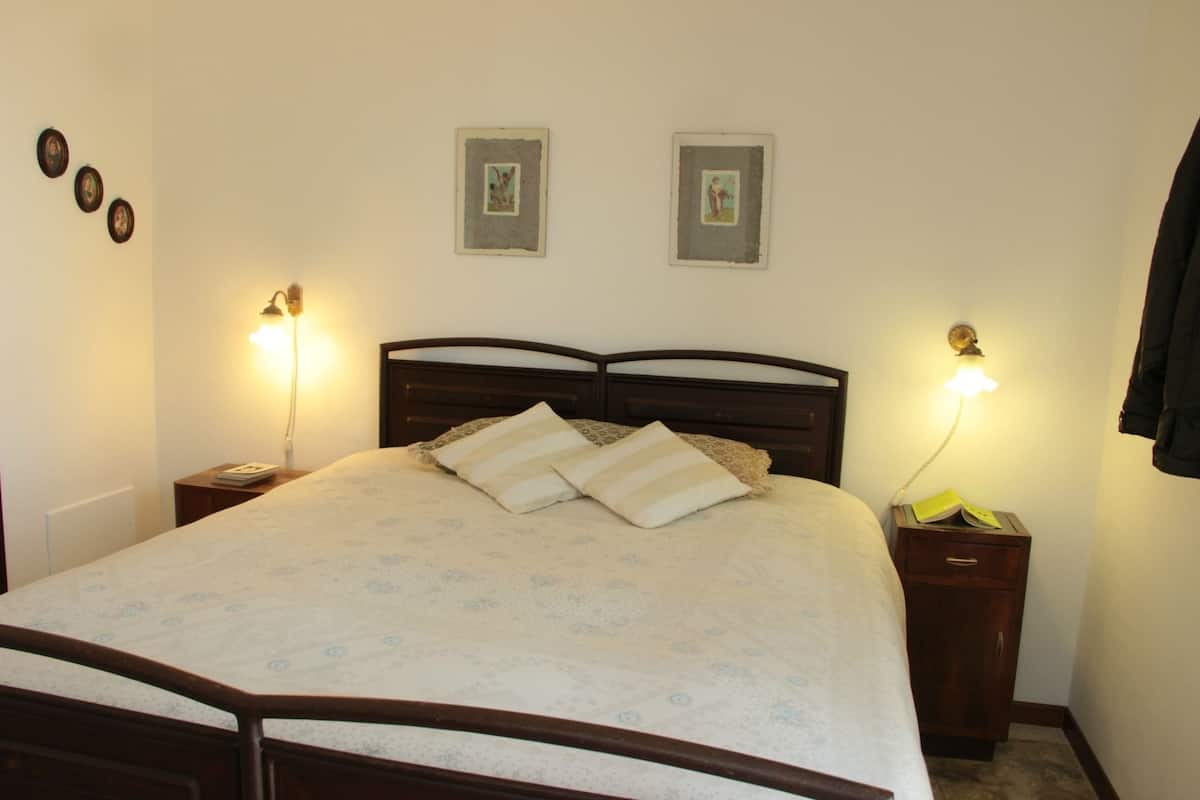 A neatly made bed with a patterned bedspread and two pillows, flanked by bedside tables with lamps.