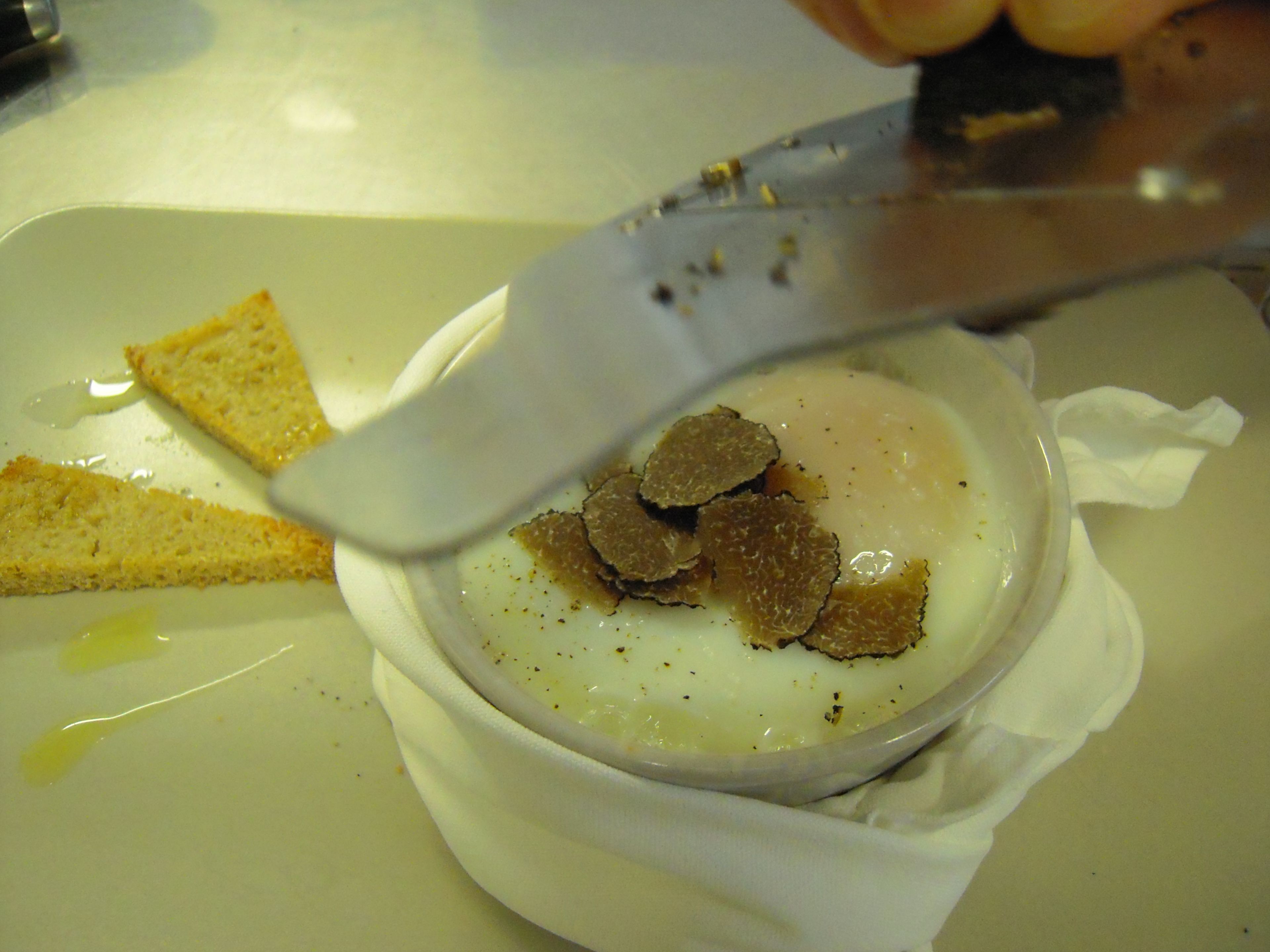 A bowl of soup with a spoon, a piece of bread, and a napkin on a plate.