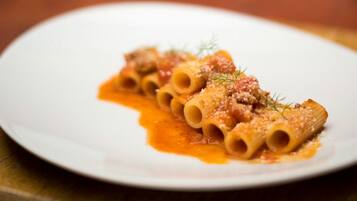 A plate of pasta with a tomato-based sauce and a garnish on a white plate.