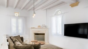 A modern living room with a sofa, fireplace, and TV. - imarkellis boutique villas (Tinos)