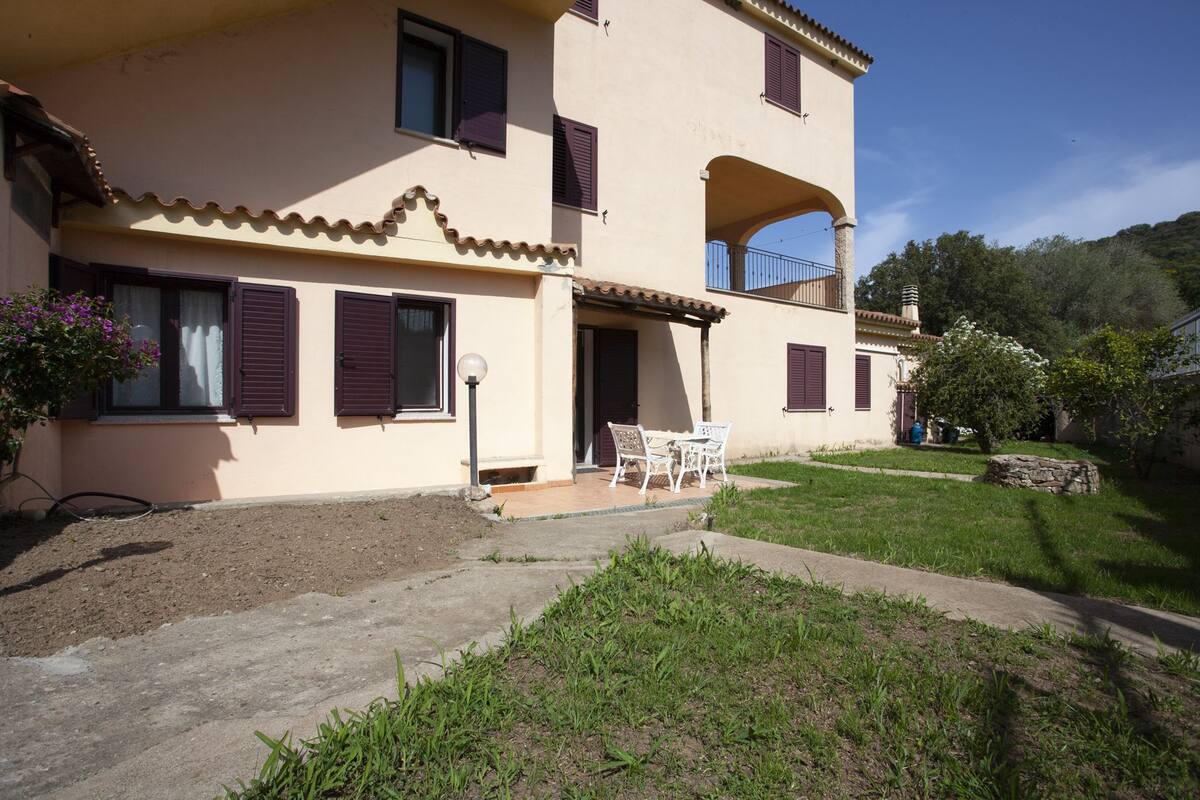 Un bâtiment à deux étages doté d’un balcon, d’une terrasse avec des meubles d’extérieur et d’un jardin.