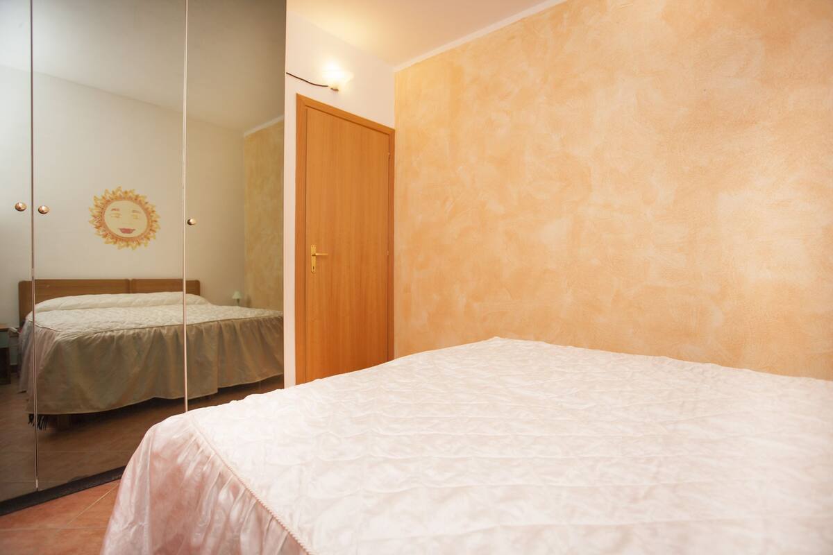 Une chambre à coucher avec un lit, une porte en bois et un miroir qui reflète la pièce.