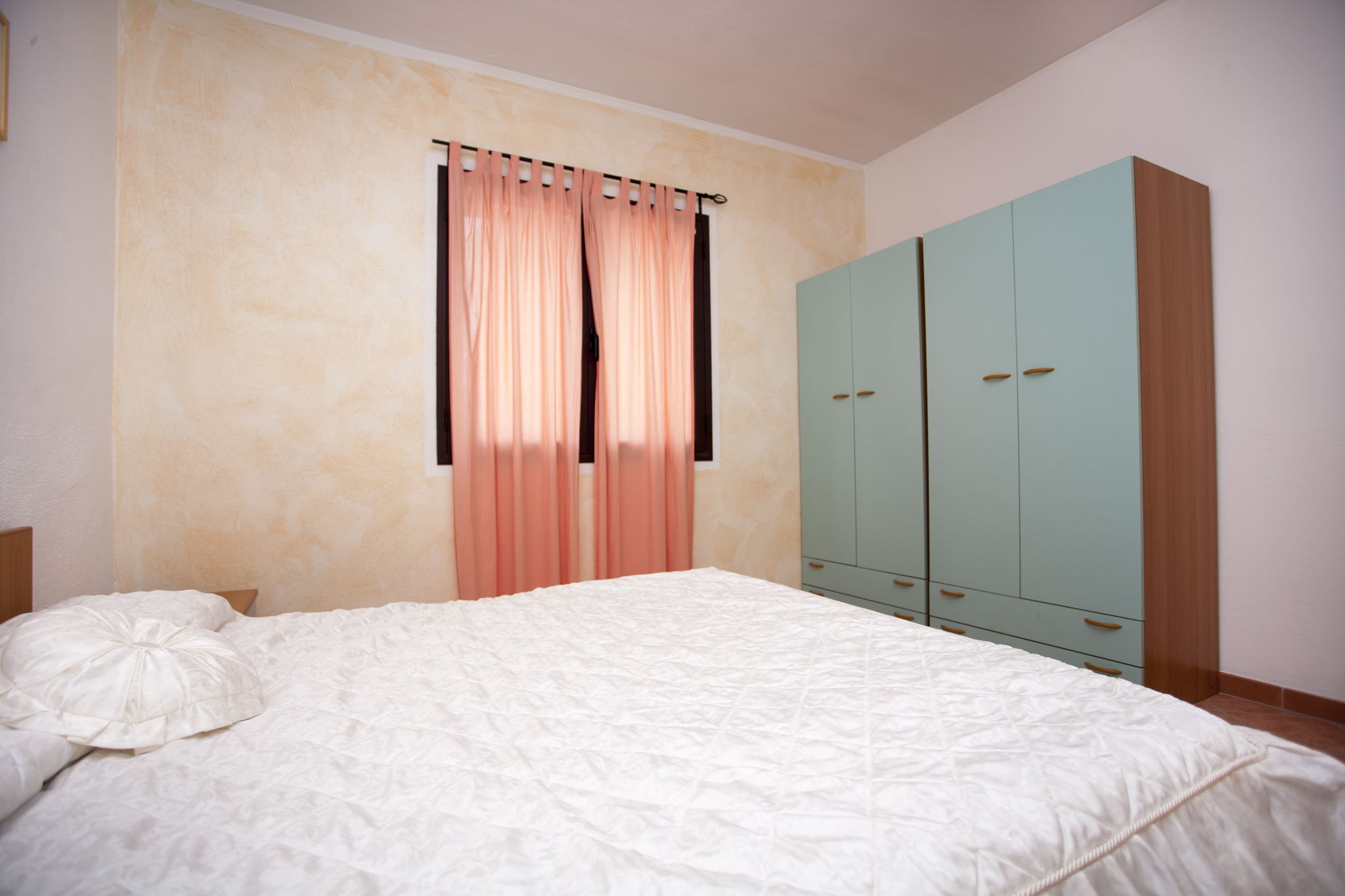 Ein Schlafzimmer mit Bett, Vorhängen und einem Kleiderschrank.
