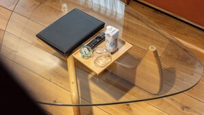Un salon moderne avec une table basse en verre, un canapé en cuir et un plancher en bois.