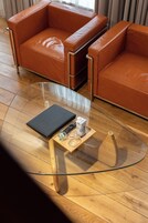 Una sala moderna con una mesa de centro de vidrio, sofá de cuero y piso de madera.