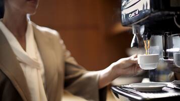 A person operating an espresso machine, holding a cup under the spout.