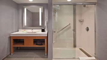 A modern bathroom with a glass-enclosed shower, a wooden vanity, and a large mirror.