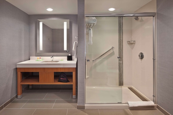 A modern bathroom with a glass-enclosed shower, a wooden vanity, and a large mirror.