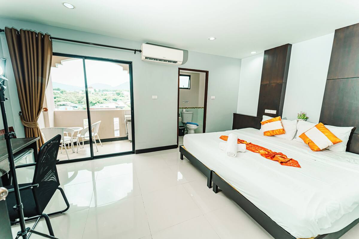 Habitación de hotel con una cama grande, un escritorio y un balcón con vistas.