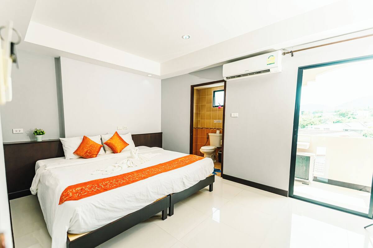 Una habitación de hotel moderna con una cama grande, un baño y un balcón.