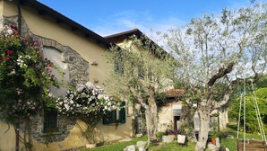 Edificio de piedra con jardín que incluye una hamaca, un árbol y un jardín de rocas.