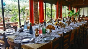Un restaurante con mesas largas dispuestas para comer, con vistas a zonas verdes al exterior.