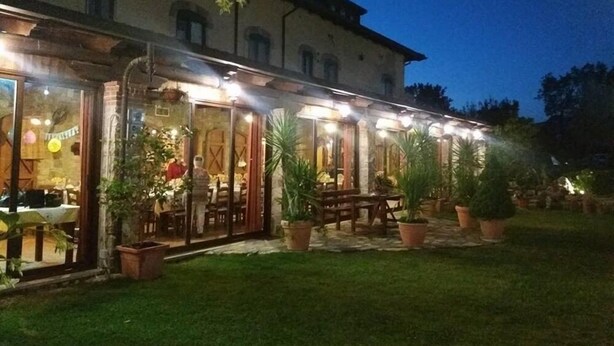 Un edificio con un área de estar al aire libre cubierta, plantas en macetas y una entrada bien iluminada.