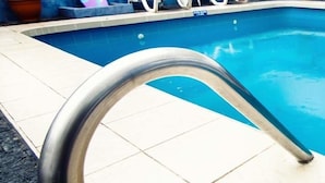 A swimming pool with a metal ladder leading into it. - Hotel El Sol (Piura)