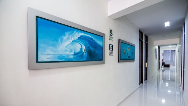 A hallway with two large framed paintings of ocean scenes on the walls. - Hotel El Sol (Piura)