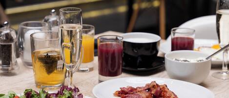 A breakfast setting with plates of scrambled eggs, bacon, and a salad, along with various beverages and a glass of champagne.